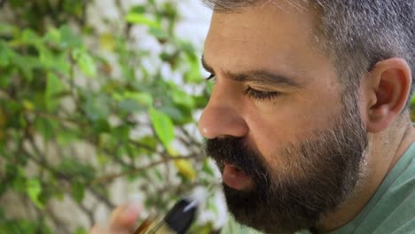 primer plano de hombres barbudos que inhalan un dispositivo de cigarrillo electrónico a la luz del día 01