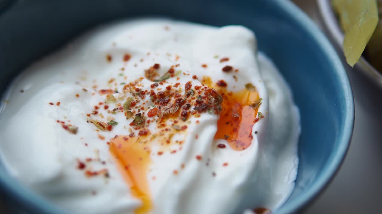 Lähikuva mausteilla ja chiliöljyllä koristellusta kermaisesta jogurttikastikkeesta