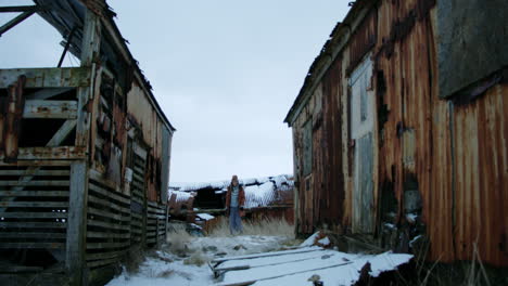 A girl moves through the space between two damaged, empty houses, surrounded by the echoes of the past.