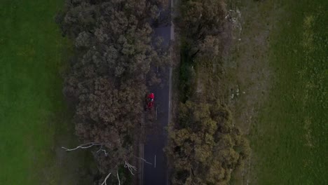 Coche-Rojo-Conduciendo-Por-Una-Carretera-Recta-Seguimiento-Aéreo-De-Arriba-Hacia-Abajo