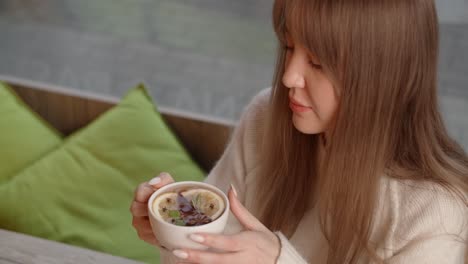 woman enjoying a cup of herbal tea in a cozy cafe