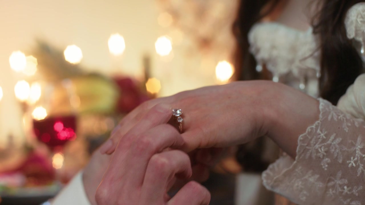Uomo mette l'anello di fidanzamento al dito della donna durante una cena romantica