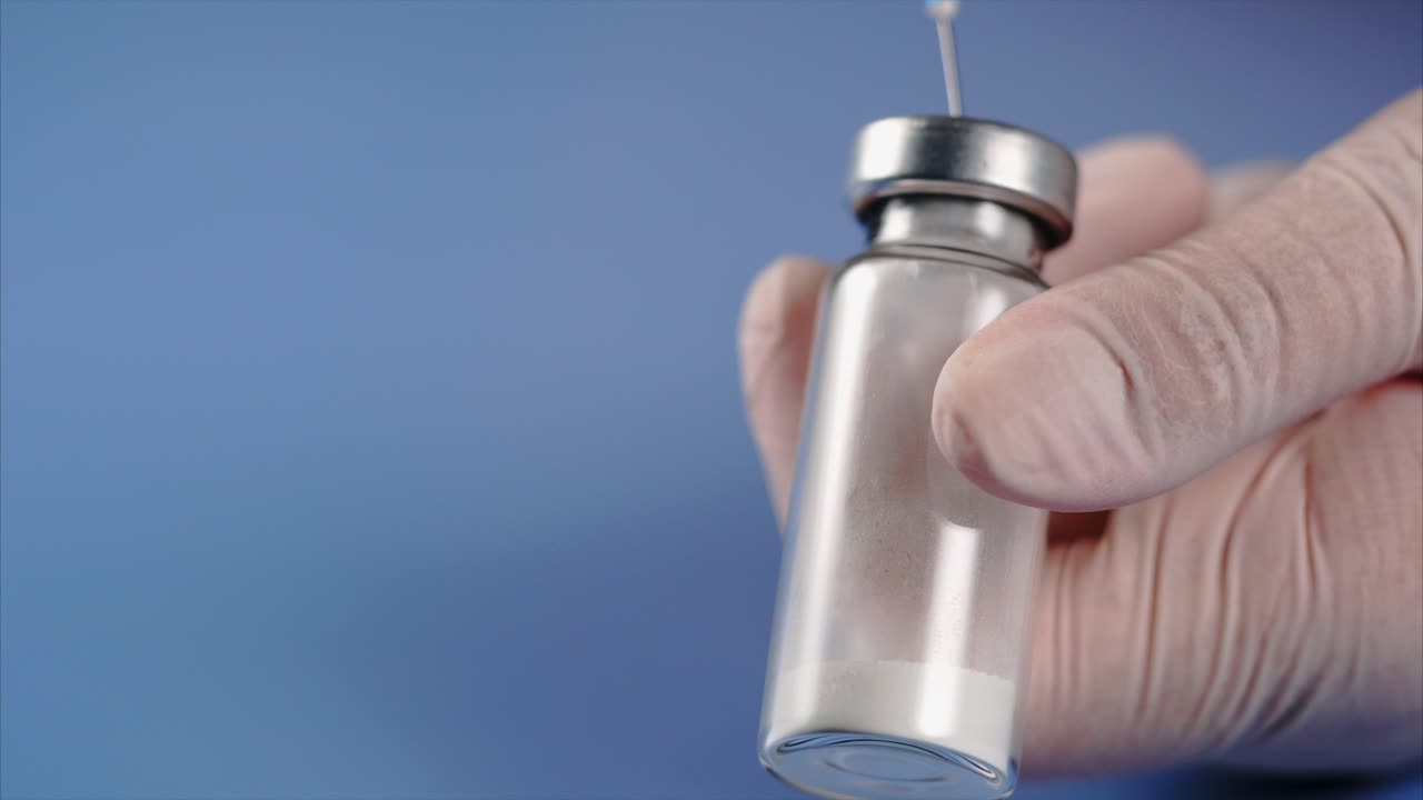 Hand holding a vial of medicine with a syringe