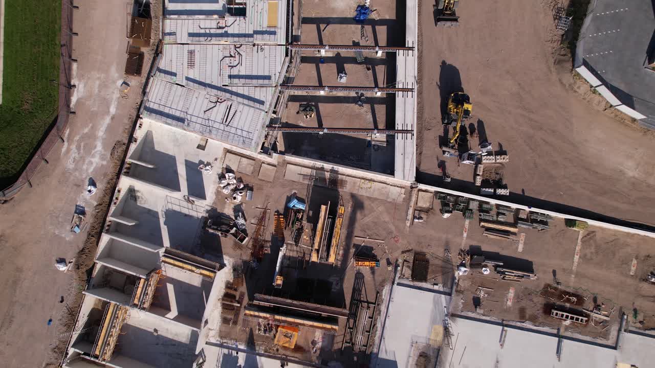 Ascending aerial movement showing part of construction site with first level of construction revealing top down wider outline of the luxury apartment Kade Zuid project and recreational port next to it