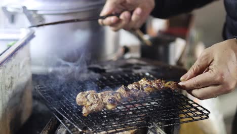 person grilling meat on a barbecue grill