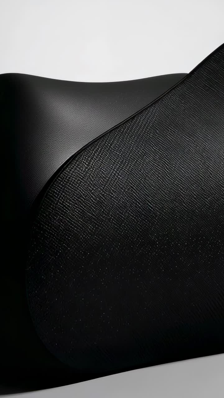 Vídeo vertical: cámara panorámica mostrando un par de cojines curvos negros en un estudio, revelando la textura