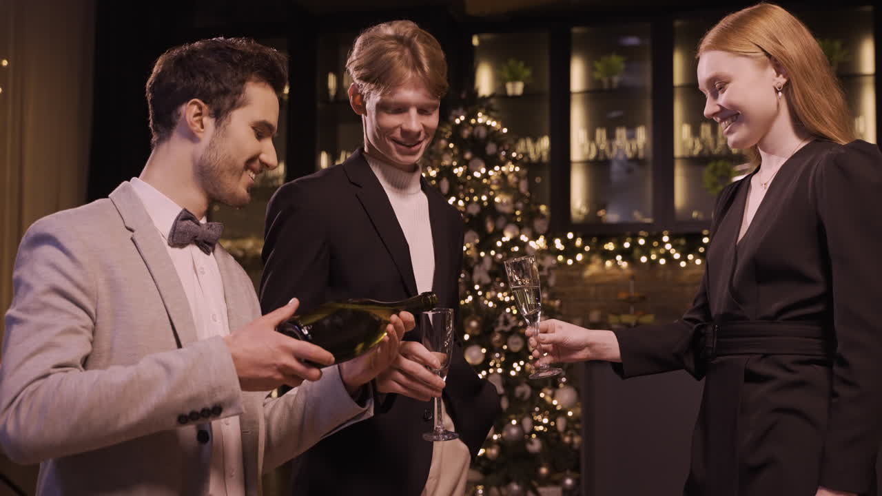새해 파티에서 한 남자가 남자와 여자의 잔에 샴페인을 붓고 건배하고 홀짝인다