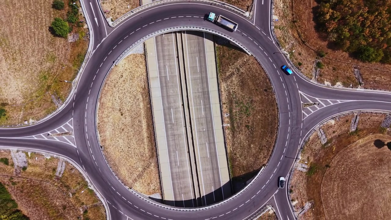 Traffic flows through a circular road junction in an open area