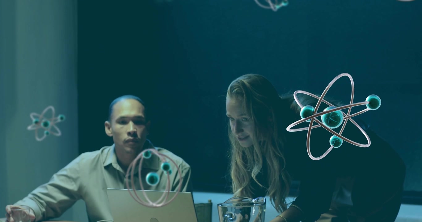Мужчина работает за ноутбуком, пока женщина указывает на экран, запуская 3D-молекулы во время технологической презентации.