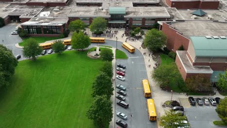 students at public school campus buildings as school buses arrive to transport learners