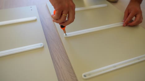 close-up of male hand assembling furniture screwing plastics in a wood plank