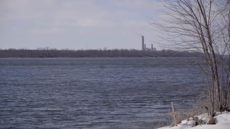 waves flowing on the river by a grave and smokestack in winter