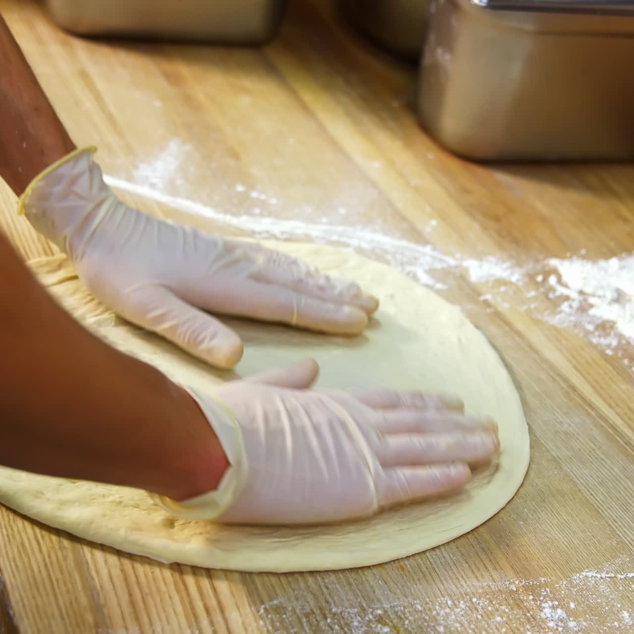 Chef forming the dough on a floured surface and kneading it with hands in a traditional pizzeria kitchen. Pizza maker prepares the dough for a tasty dish