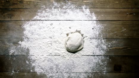 baker throws dough onto wooden table upper view slow motion