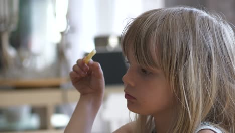 everyday life scene in a family home, young girl eating french fries