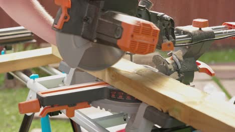 slow motion shot of a carpenter using a saw to cut through decking boards with dust rising