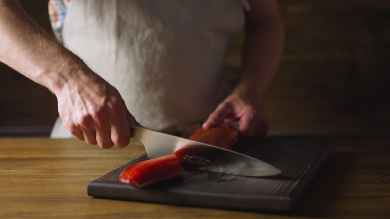 Chef in apron chops delicatessen cool smoked salmon fillet