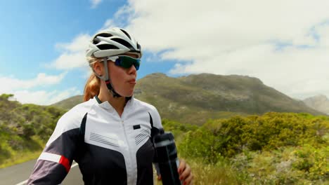 Ciclista-Femenina-Bebiendo-Agua-En-La-Carretera-Rural-4k