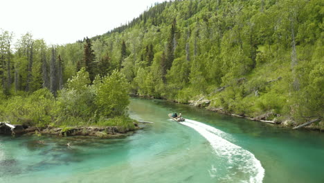 a pair of jet boats speed around corner of beautiful blue river in remote alaskan wilderness