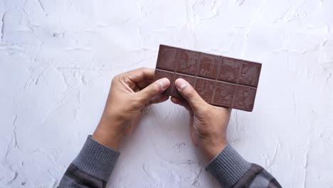 hands holding a dark chocolate bar