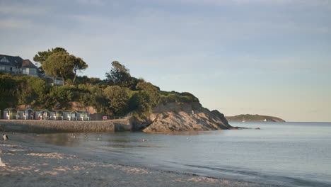 Water-gently-laps-ashore-Swanpool-Beach-at-golden-hour,-wide