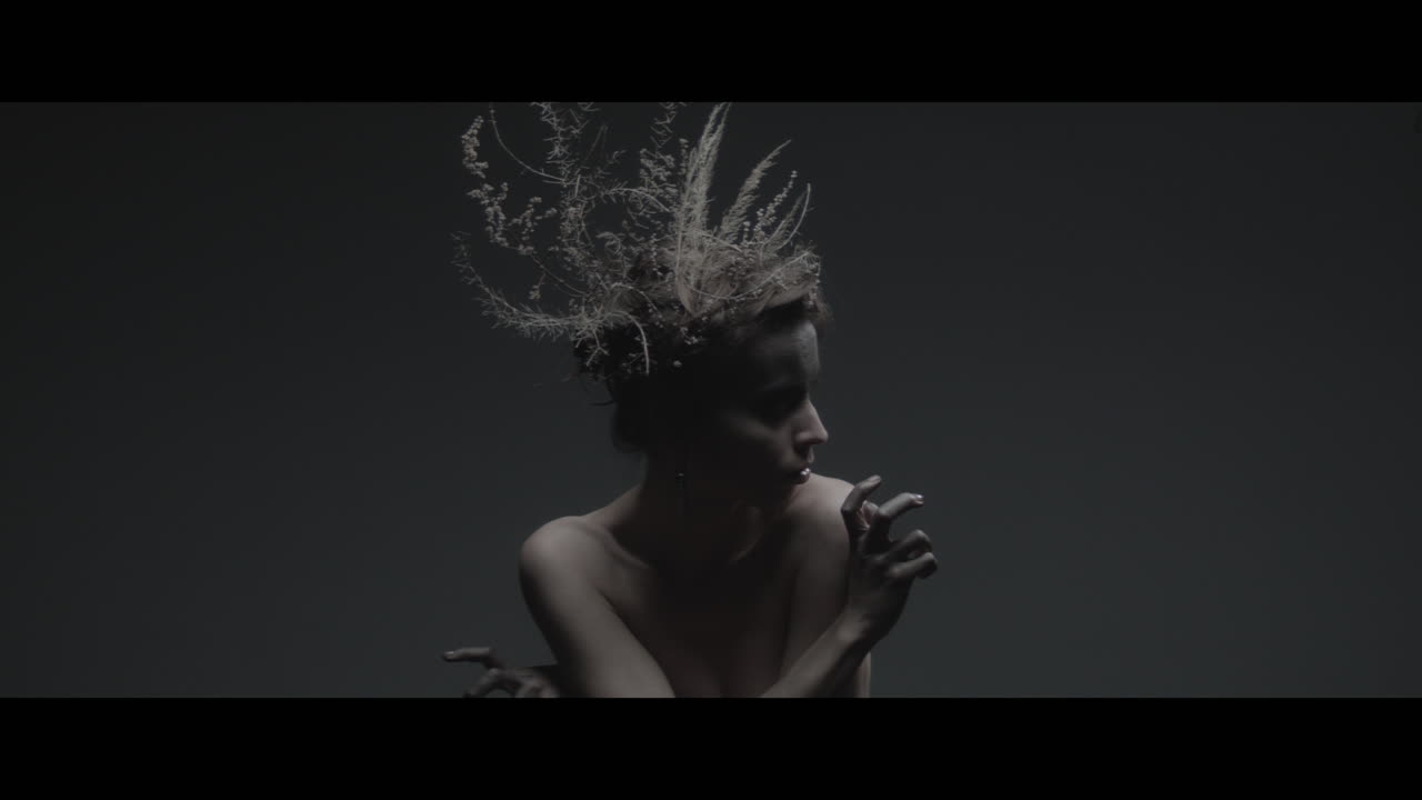 A woman dressed as mother nature moves slowly in a dance-like motion