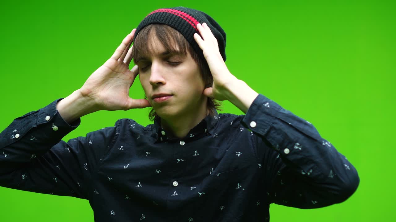 젊은 남자는 제거 가능한 크로마 키 배경에 머리를 들고 진정합니다.