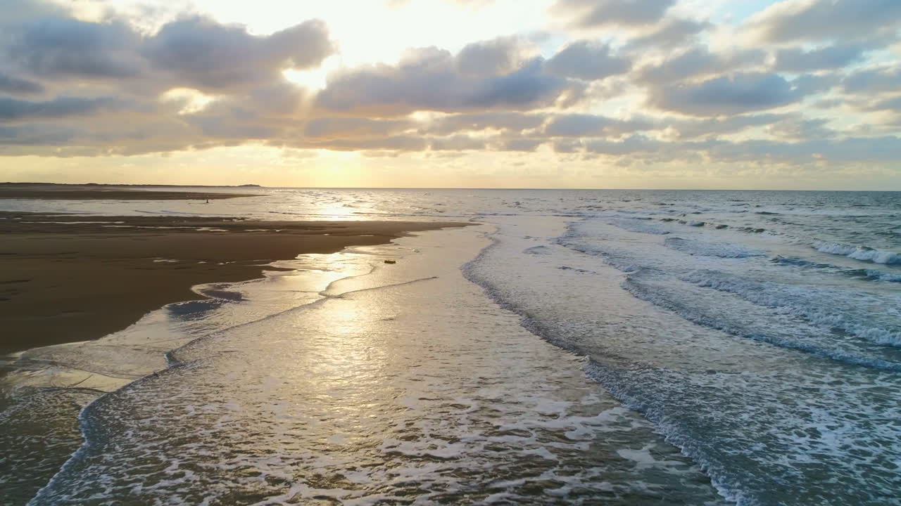 Stunning Beautiful Low Aerial Drone Shot Over Small Waves Breaking on Sandy Beach at Golden Hour Sunset