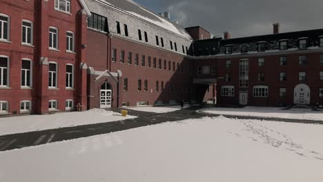 Rote-Backsteinfassade-Der-McCreer-Hall-Der-Bischofsuniversität-Mit-Fußspuren-Im-Schnee-Im-Winter-In-Lennoxville,-Sherbrooke,-Quebec