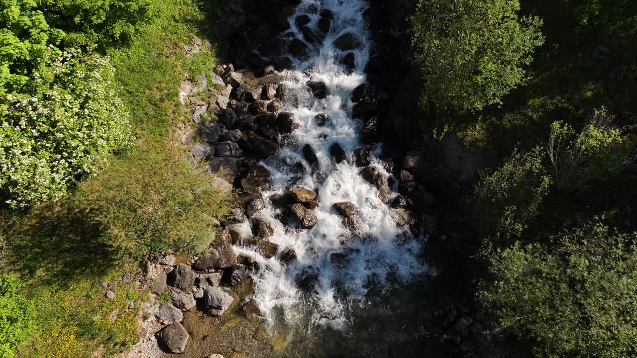 Top-down aerial view of a mountain river flowing over rocks and stones in Weesen, Switzerland, capturing the concept of natural dynamism and untouched wilderness