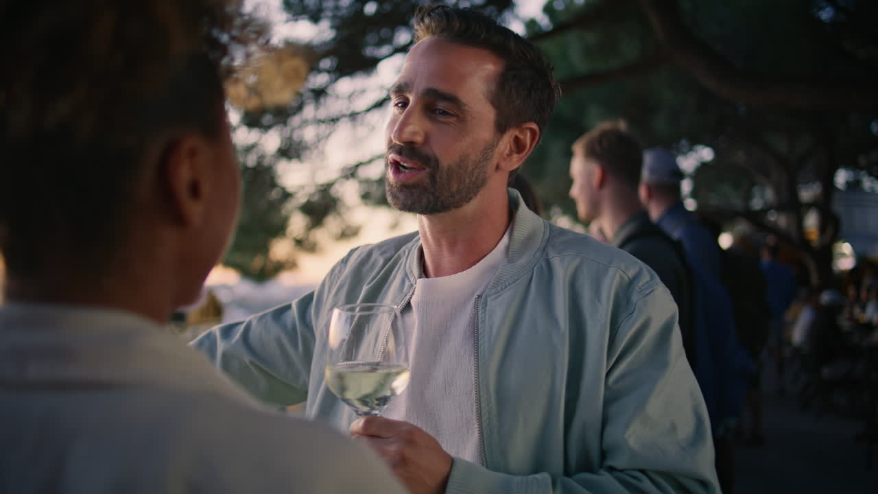 una pareja bronceada disfrutando del vino al atardecer, el paisaje urbano en primer plano, un hombre con un vaso de vino
