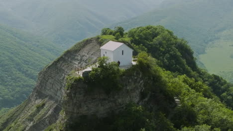 Arc-shot-of-wild-forest-surrounding-a-medieval,-secluded-church-nearby-Tsveri