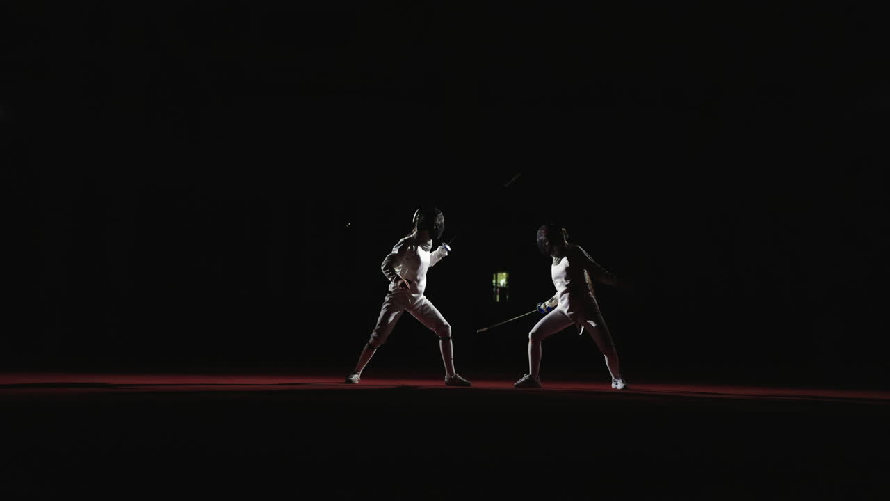 Two fencers face each other on a red stage during a fencing competition