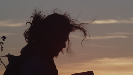 Long-hair-waving-in-the-wind,-Tourist-at-sunset-on-the-horizon