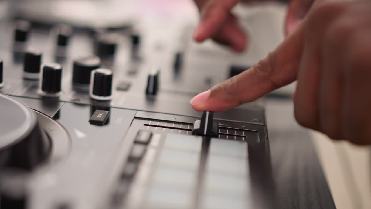 Primer plano de manos de DJ en la mesa de mezclas ajustando faders y perillas, iluminación de estudio íntima resalta la técnica de la punta de los dedos, control de precisión de canales y pads para producción de música electrónica, enfoque táctil