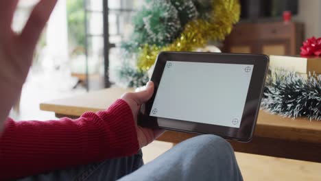 happy albino african american man wearing santa hat using tablet with copy space at christmas