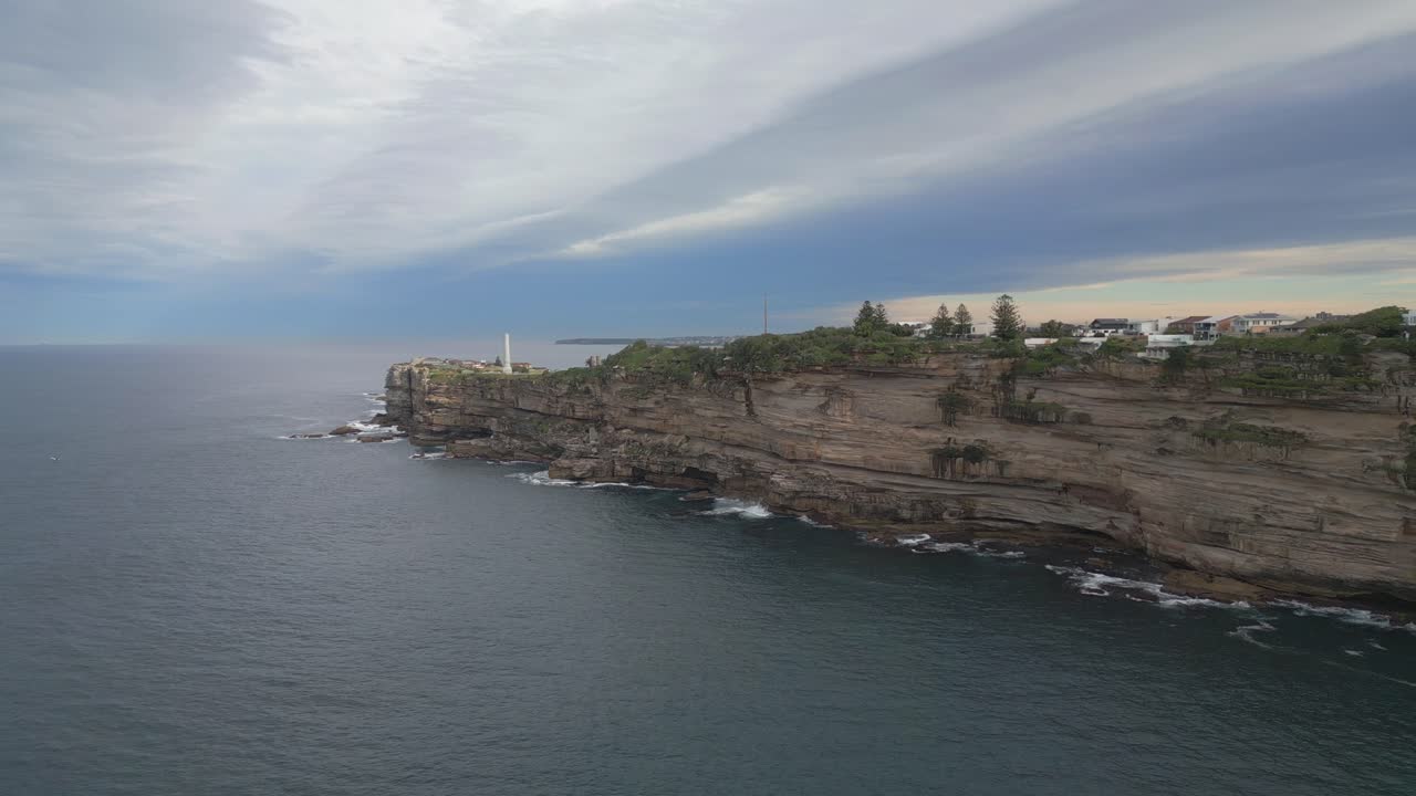 Coastal cliffside cityscape with lighthouse