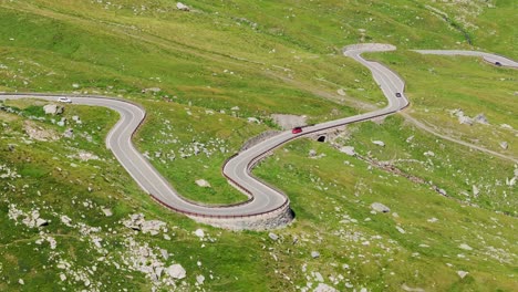 scenic alpine route as red car twists through sharp turns in the italy mountains