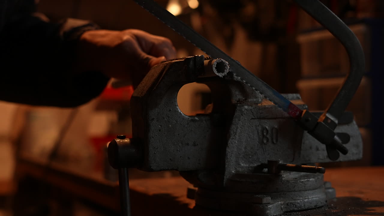 hombre usando una sierra para metales, cortando un tubo