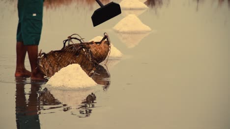 Low-section-view-of-a-salt-field-worker-harvesting-salt-in-the-famous-salt-farms-of-Kampot,-Cambodia