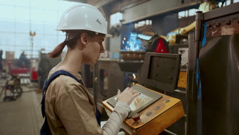 female worker operating welding machine in industrial plant