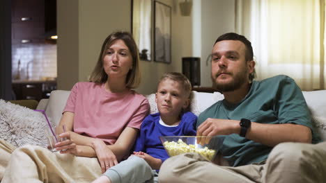 Familie-Sitzt-Auf-Dem-Sofa-Und-Schaut-Sich-Einen-Film-An