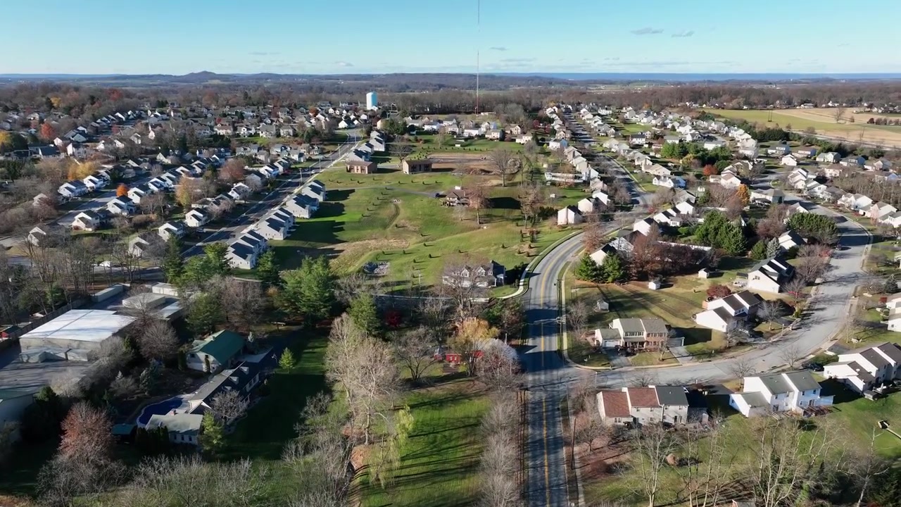 Aerial establishing shot of new developed housing area with intersection during sunny day. Autumn day with blue sky in November. Scenic suburb housing area in United States. Wide shot.