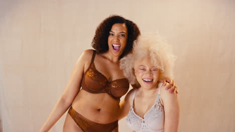 studio shot of two female friends in underwear dancing and smiling promoting body positivity