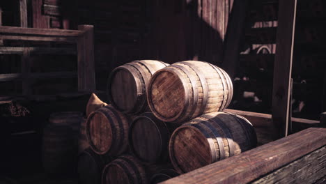 stacked wooden barrels in a rustic storage area during daylight hours