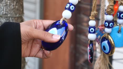 close-up of a hand holding a blue evil eye charm