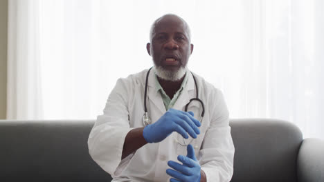 Portrait-of-male-african-american-doctor-showing-how-to-cover-your-mouth-while-having-a-videocall