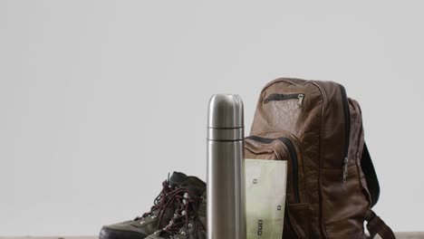 equipo de campamento con mochila, termo y botas y espacio de copia sobre fondo blanco
