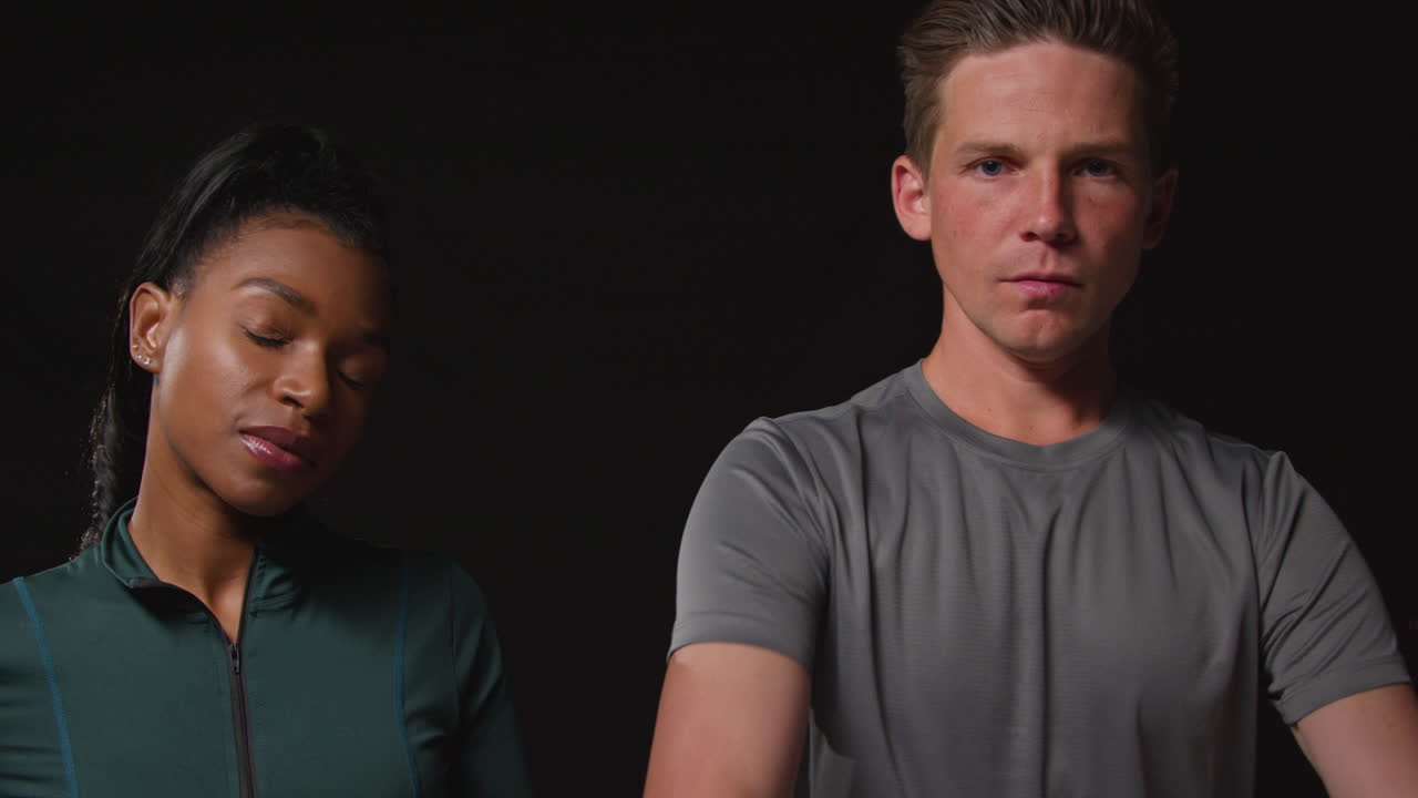 검은색 배경에 찍은 피트니스 옷을 입고 훈련하는 진지하고 결단력 있는 남녀 운동선수들의 스튜디오 초상화