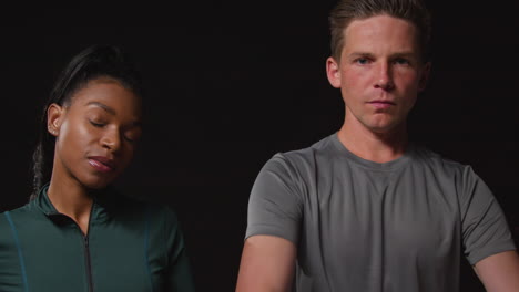 studio portrait of serious and determined male and female athletes training in fitness clothing shot against black background